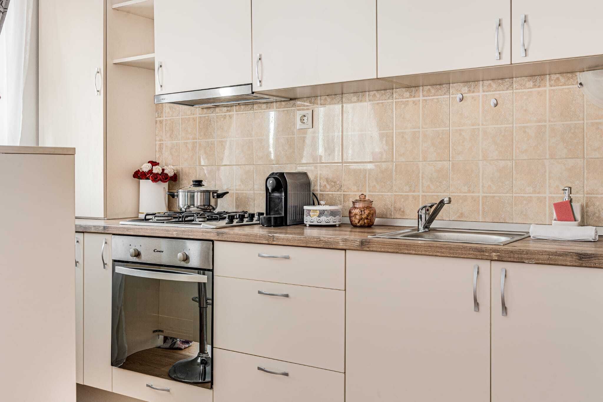A kitchen with a stove, oven, sink, and cabinets.