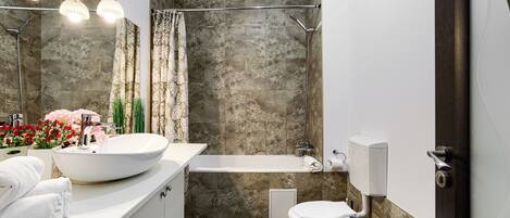 Un baño moderno con un lavamanos grande de color blanco, una bañera y un inodoro.