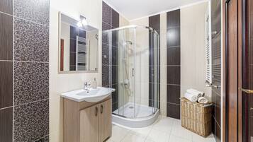 A modern bathroom with a glass-enclosed shower, a sink, and a mirror.