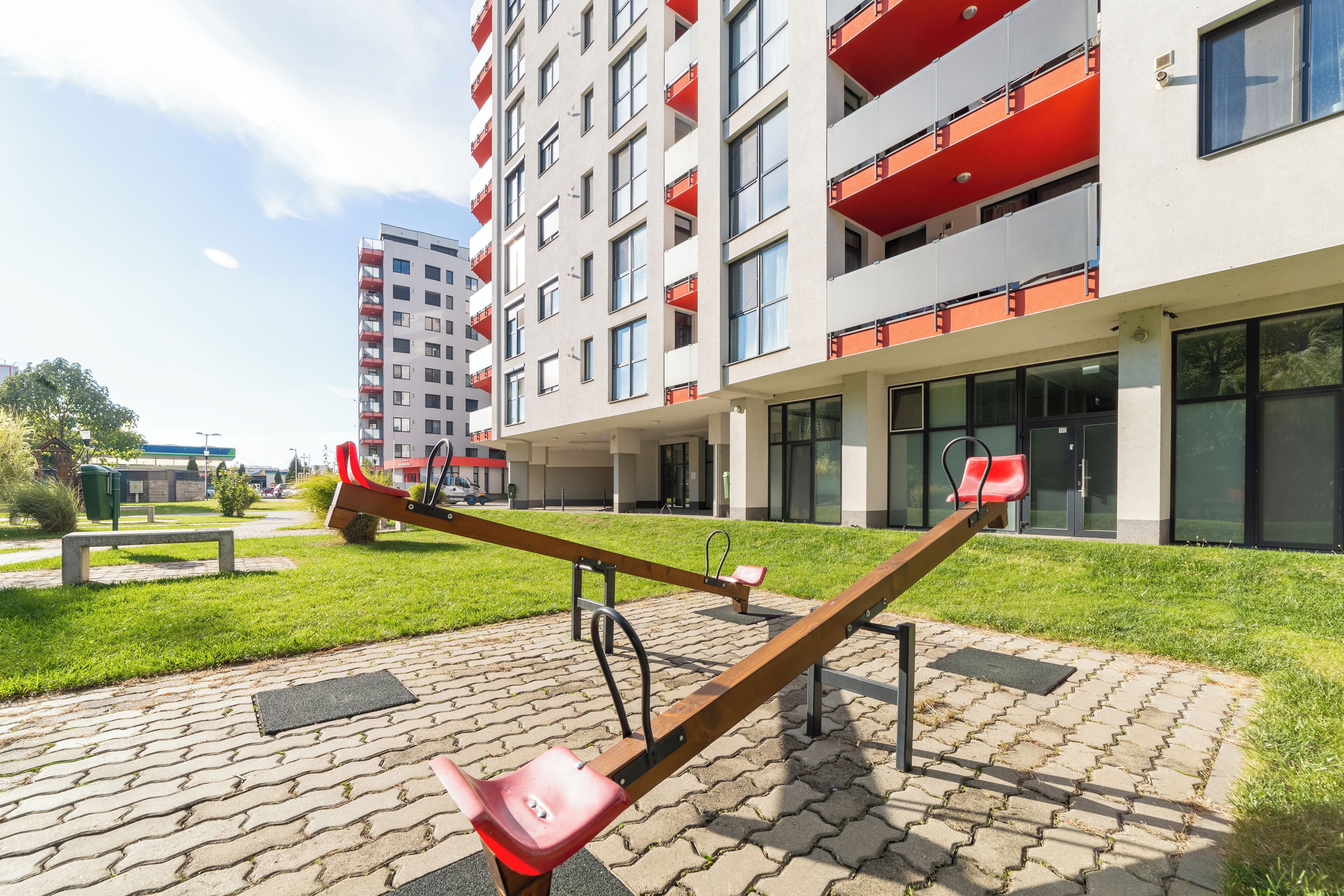 A seesaw in a courtyard with a modern building in the background.