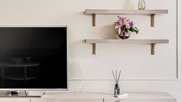 Una sala de estar moderna con un televisor de pantalla plana, un mueble color beige y estantes de madera con adornos.