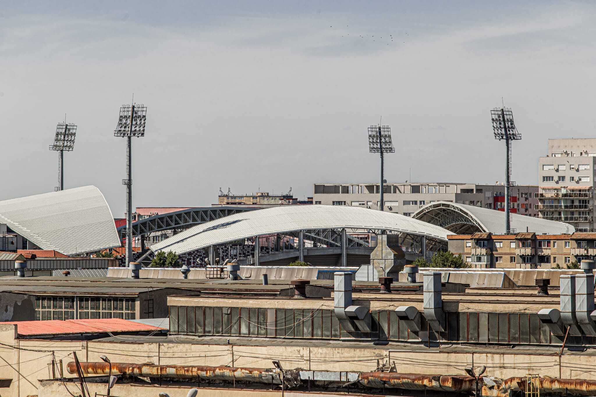 A stadium with a large, white, curved roof structure and multiple light poles.