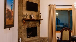 A cozy living room with a stone fireplace, wooden ceiling, and a large window with curtains. - Four 6666 - Come experience a sleepover with our Giraffe, Puzzles and Jigsaw! (Valley View)