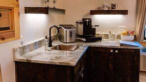 A kitchen with dark wood cabinets, a marble countertop, a coffee maker, a toaster, and a bowl of chips. - Four 6666 - Come experience a sleepover with our Giraffe, Puzzles and Jigsaw! (Valley View)