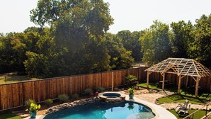 A backyard with a swimming pool, a wooden pergola, and a stone patio. - Four 6666 - Come experience a sleepover with our Giraffe, Puzzles and Jigsaw! (Valley View)