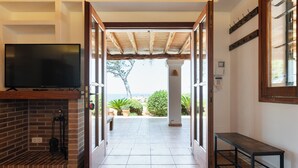 Una habitación con televisión, chimenea, un banco y vistas al exterior.