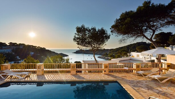 Un área de piscina con sillones de descanso y vista al mar.