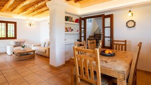 Una sala de estar acogedora con una mesa de comedor de madera, sofás blancos y una estantería.