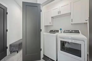 A laundry room with a washing machine, dryer, and cabinets.