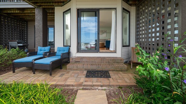 Un patio cubierto con mobiliario exterior y vistas al interior.