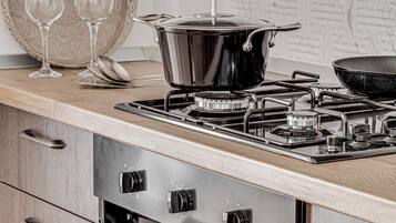 A kitchen with a stove, oven, and a decorative plate with glasses.