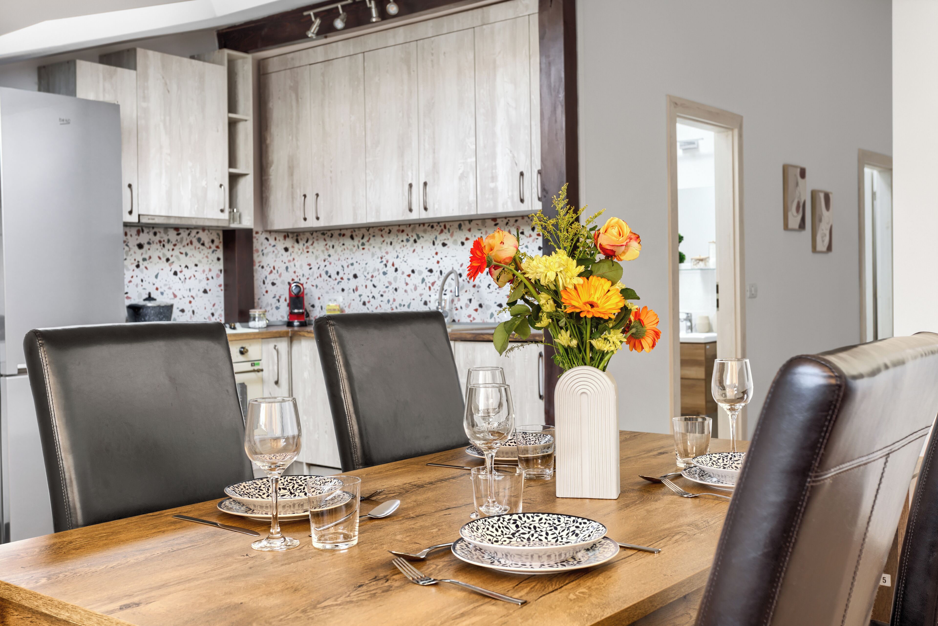 A dining table set with plates, glasses, and cutlery, with chairs around it.