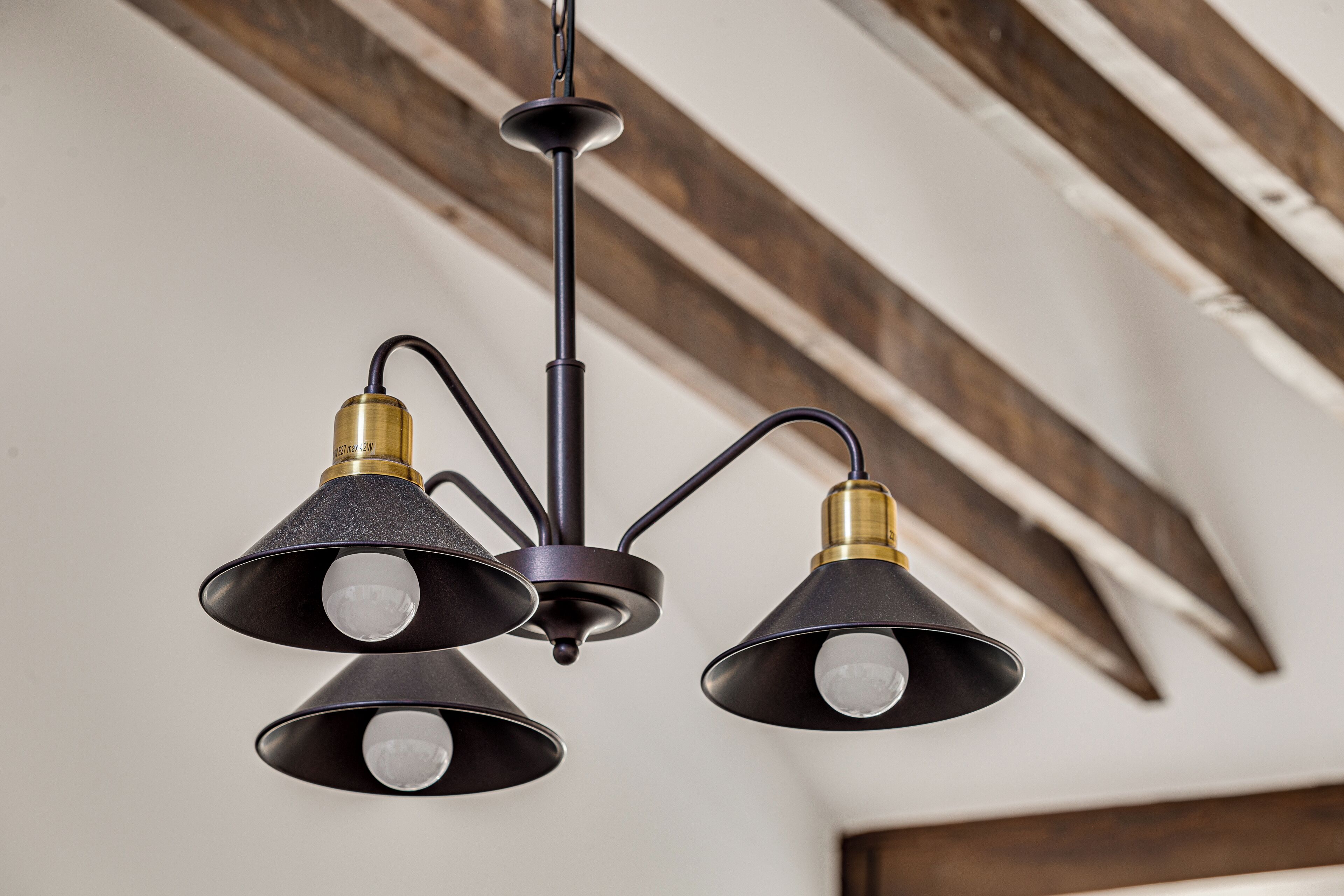 A ceiling light fixture with three lampshades and a central support.