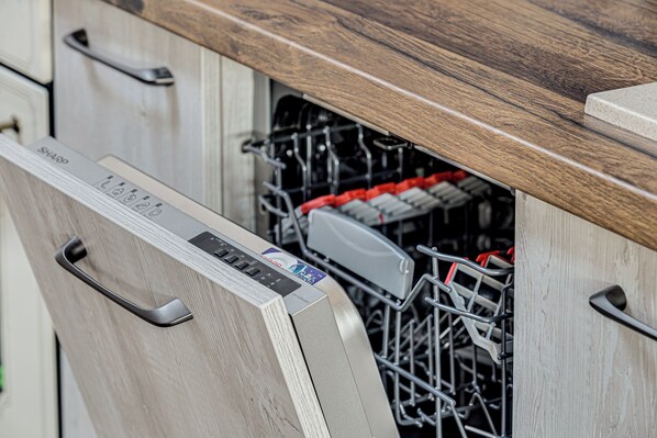 Una cocina moderna con lavavajillas, armarios de madera y un tirador metálico.