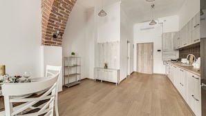 Une cuisine moderne avec des meubles blancs, une arche en briques et un plancher en bois.