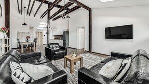 Un salon moderne avec des canapés en cuir, une table basse en bois et un téléviseur à écran plat fixé au mur.