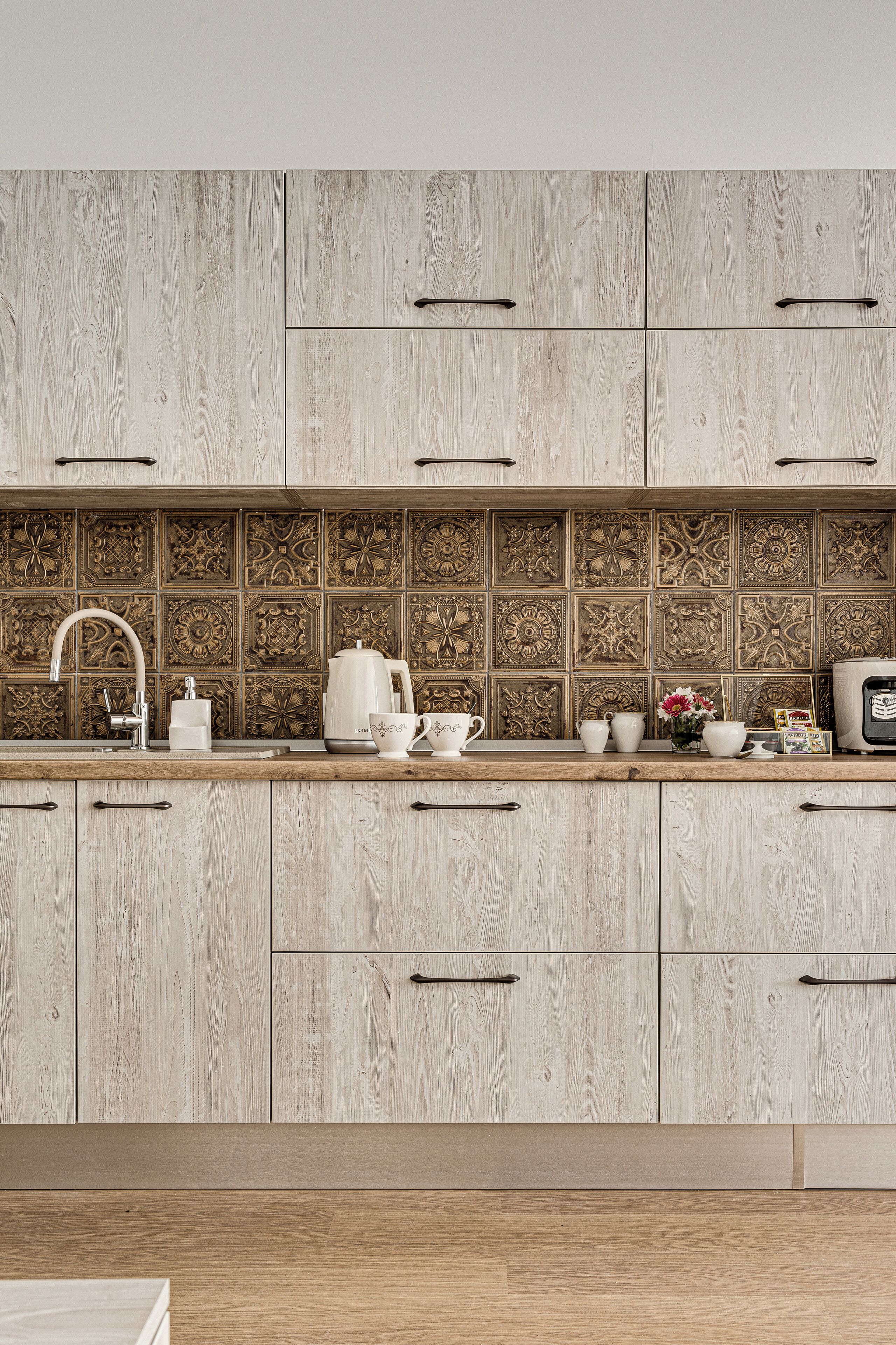 Una cocina con armarios de madera, salpicadero de azulejos y varios utensilios.