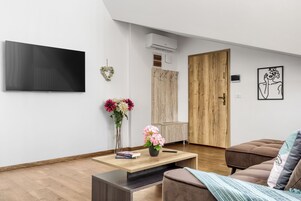 Apartamento família, 2 quartos, sacada, vista para a cidade | Área de estar | TV de tela plana 40 cm com canais a cabo