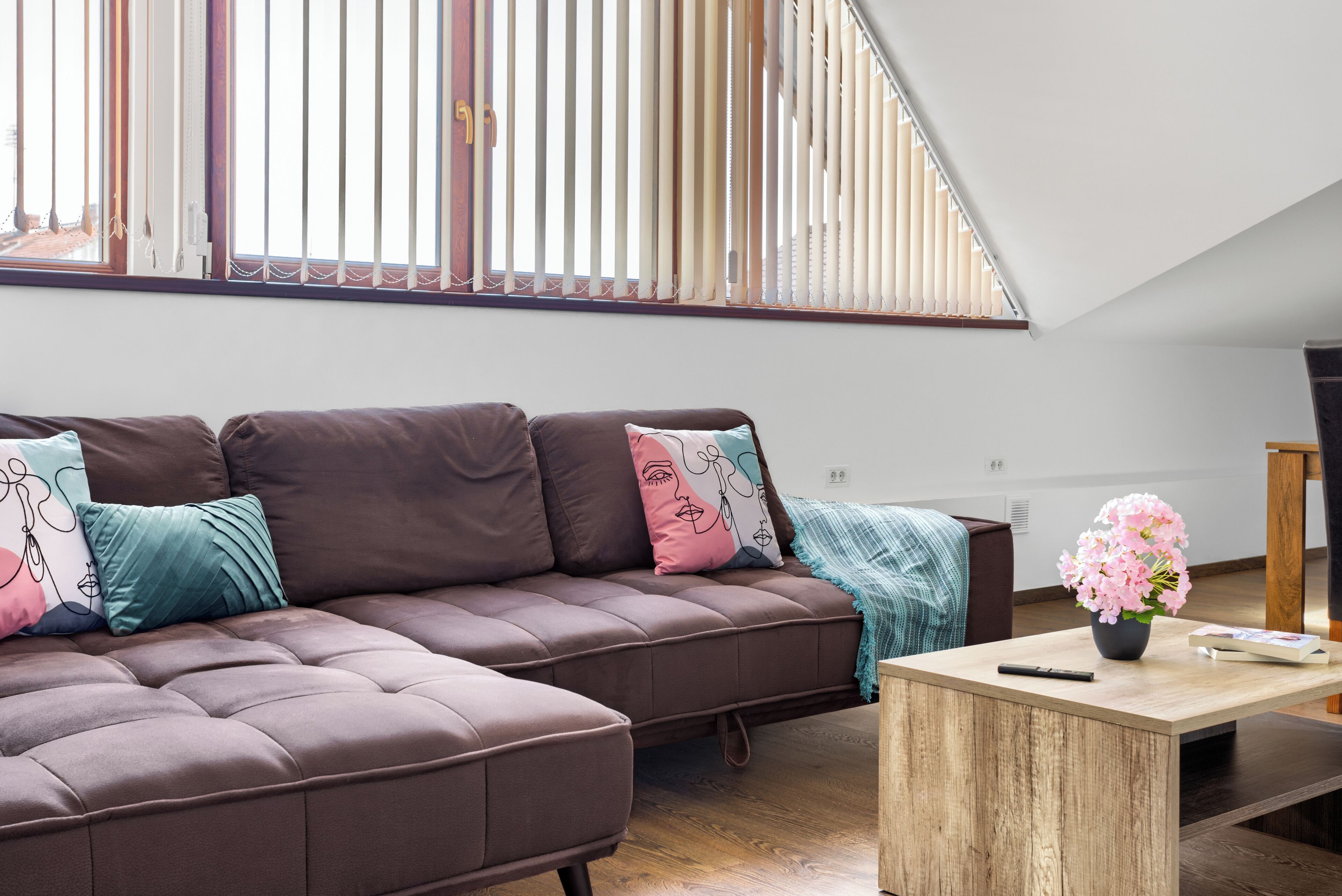 A modern living room with a sectional sofa, a wooden coffee table, and a view of the outdoors through large windows.