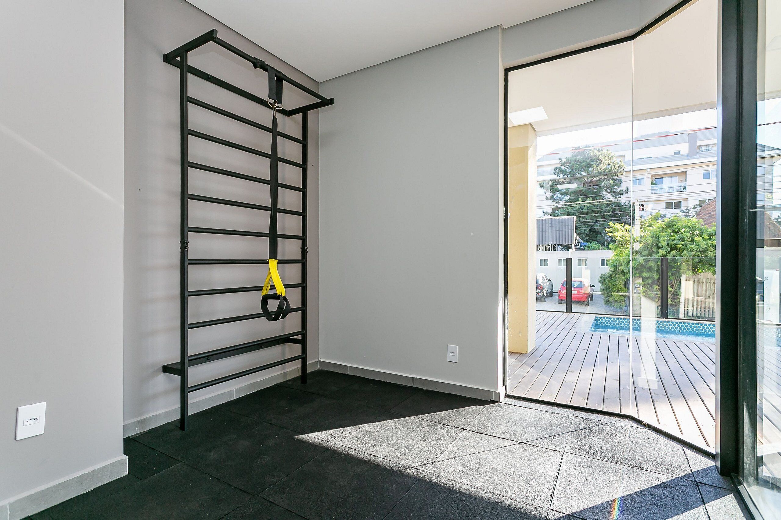 A room with a pull-up bar, a small window, and a view of a balcony with a pool.