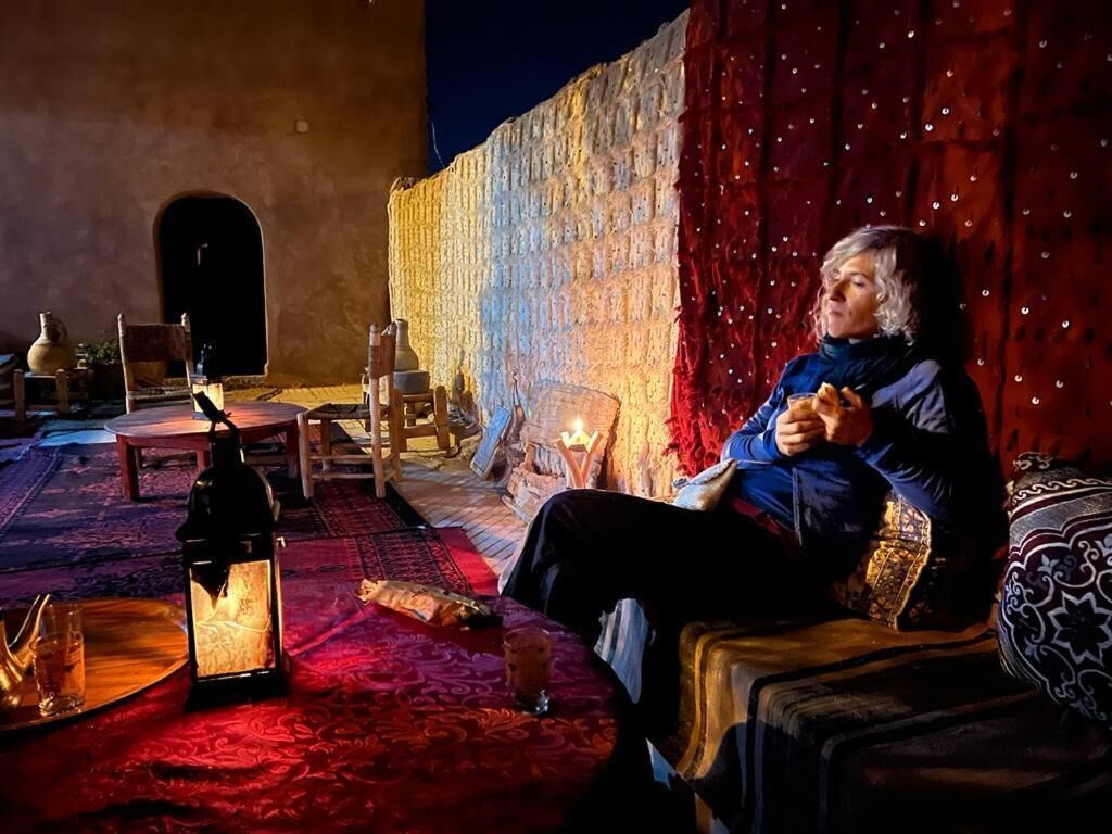 A cozy room with a patterned rug, a wooden table with a lantern, and a red curtain.