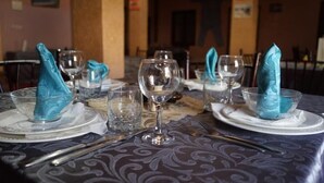 A dining table set with blue napkins, clear glassware, and silverware. - Riad Assia (Foum Zguid)