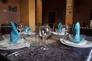 Una mesa de comedor dispuesta con servilletas azules, cristalería transparente y cubiertos.