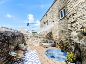 En bygning i sten med et spabad, fletningsmøbler og en tæppe med mønster.