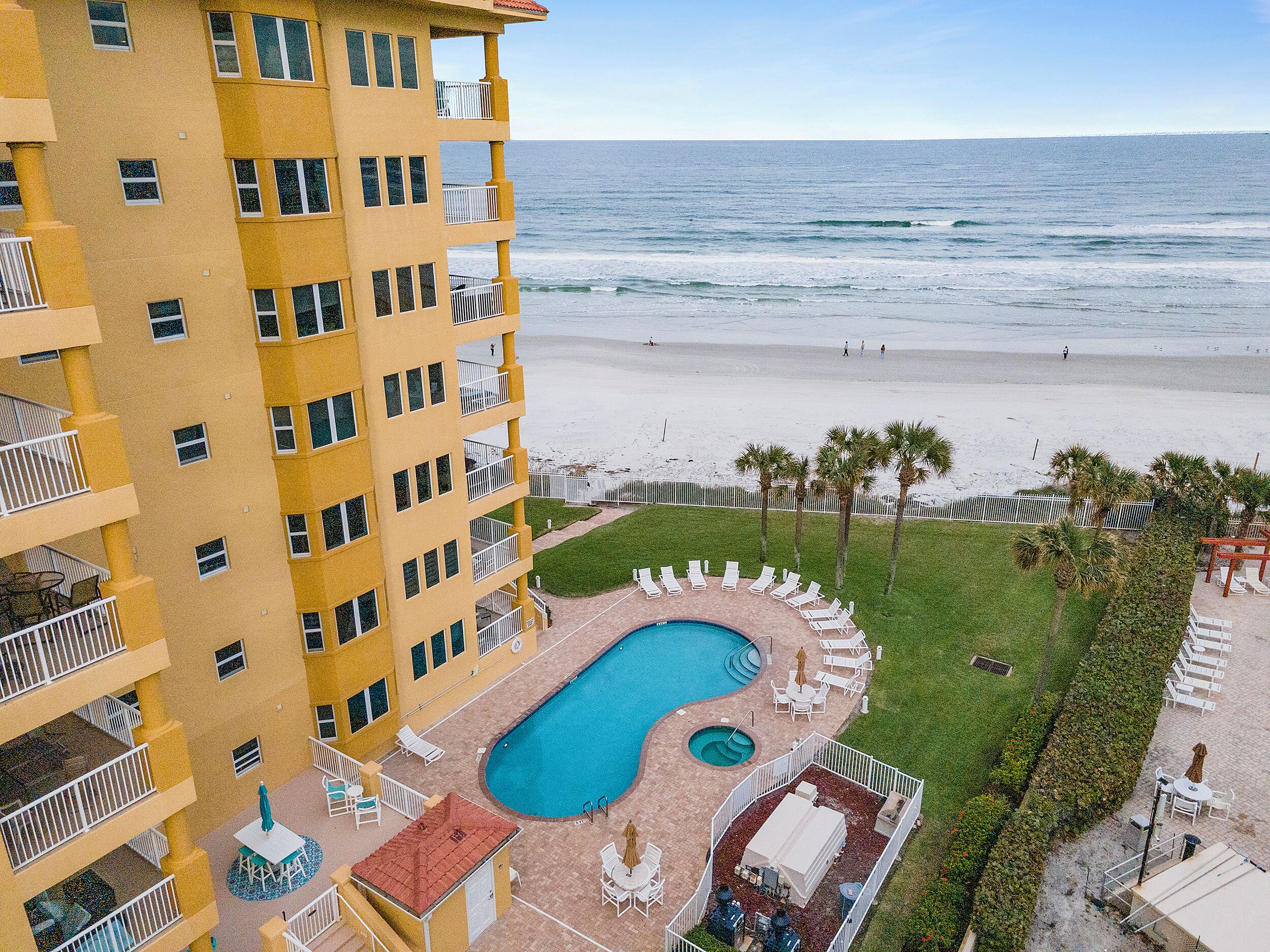 A hotel with a pool, beach view, and multiple balconies.