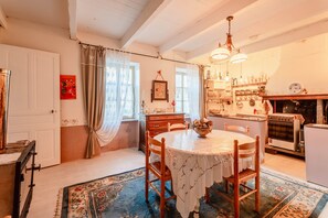 A cozy kitchen with a round table, chairs, a chandelier, and a stove.