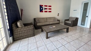 Una sala de estar con un sofá, dos sillones, una mesa de centro y una bandera en la pared.