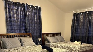 Habitación de hotel con dos camas, cada una con ropa de cama y almohadas estampadas, un cabecero de madera y suelo de baldosas.