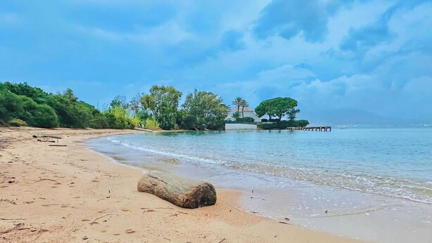 A beach with a large rock in the foreground, calm water, and a pier extending into the water. - A serene stay with a sea view (Grosseto-Prugna)