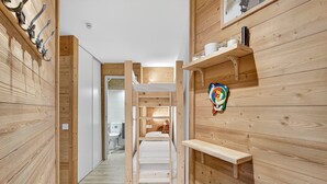 A narrow hallway with wooden walls, a bunk bed, and a shelf with items.
