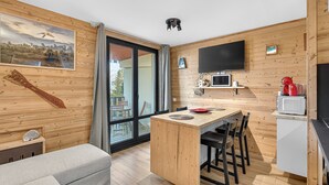 A modern kitchen with a wooden interior, a dining area, and a large window.