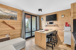 A modern kitchen with a wooden interior, a dining area, and a large window. - Studio "Mbs Pra Loup" with Mountain View, Balcony and Wi-Fi (Uvernet-Fours)