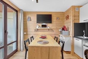 A wooden-paneled room with a dining table, chairs, a TV, a microwave, and a sink. - Studio "Mbs Pra Loup" with Mountain View, Balcony and Wi-Fi (Uvernet-Fours)