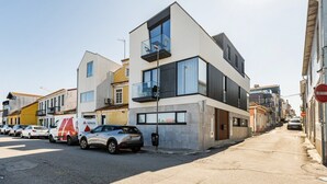 A modern building with a flat roof, large windows, and a balcony.