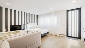 A modern bedroom with a bed, bedside table, TV, and a sofa.
