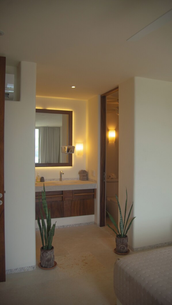 A hotel bathroom with a sink, mirror, and two potted plants.