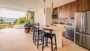 Una cocina moderna con una isla grande, electrodomésticos de acero inoxidable y vistas al exterior.