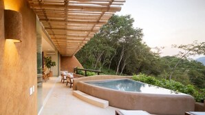 Un área de piscina moderna al aire libre con una pérgola de bambú, asientos y abundante vegetación de fondo.