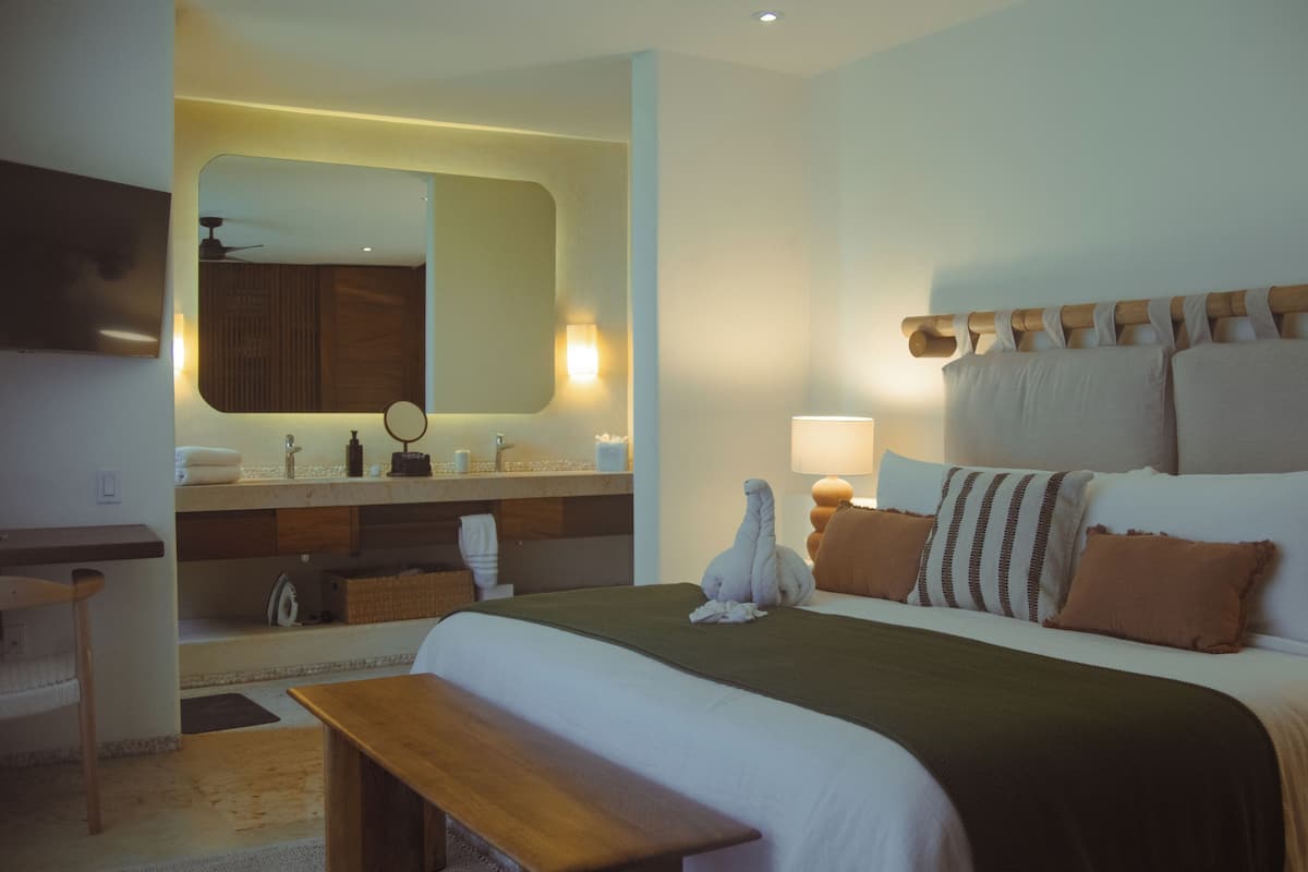 Ein Hotelzimmer mit Bett, Nachttisch, Lampe und Spiegel.