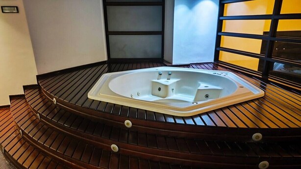 Zona de spa con jacuzzi y escalones de madera que lo conducen.