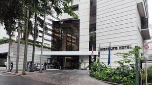 Una entrada de hotel moderna con fachada de vidrio, un área de estacionamiento y un camino peatonal.