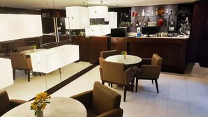 Una cocina moderna con armarios blancos, una zona de bar y un comedor con mesas y sillas redondas.