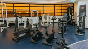 Un gimnasio con diversos equipos de ejercicio, incluyendo cintas de correr, bicicletas estáticas y máquinas de pesas.