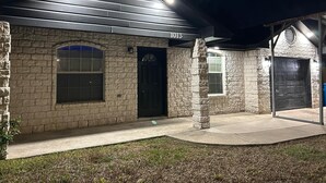 A stone house with a black door, a garage, and a number '1013' above the door.