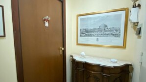 Ein Korridor mit einer Holztür, einem gerahmten Bild an der Wand und einem Schrank mit Marmorplatte.