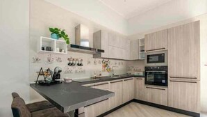 A modern kitchen with light wood cabinets, a black countertop, and a built-in oven. - Guest House San Giacomo*Holidays in Apulia* in the centre to 5 min Teatro Curci (Barletta)